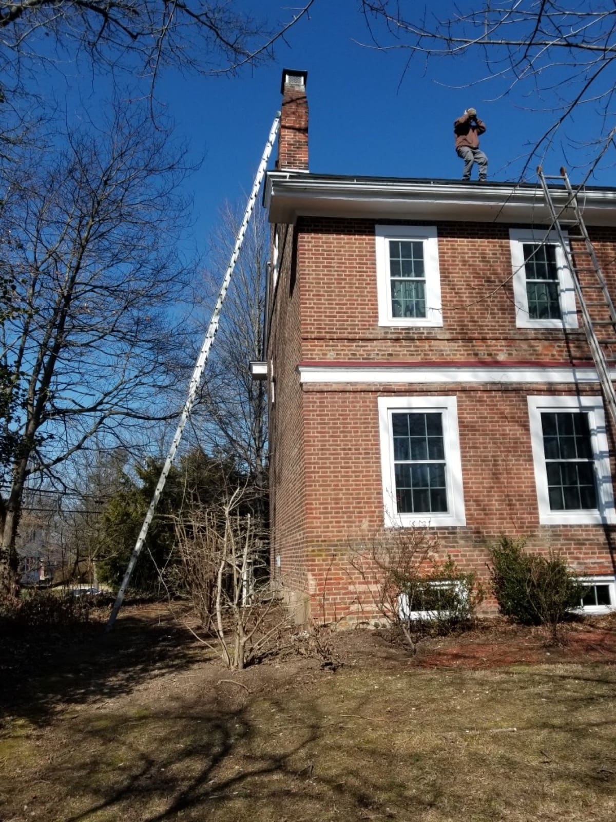 Ladder set for a roofline exclusion visit on a brick colonial